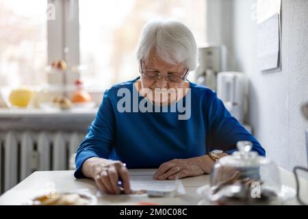 Seniorin, die Finanzberichte ausfüllt Stockfoto