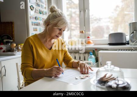Seniorin, die Finanzberichte ausfüllt Stockfoto