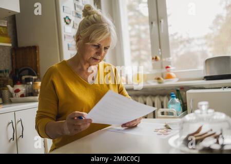Seniorin, die Finanzberichte ausfüllt Stockfoto
