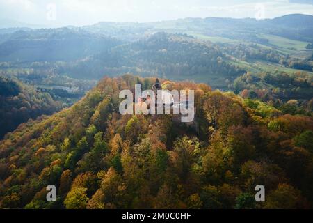 Luftaufnahme von oben auf Schloss Grodno in Zagorze mit schöner Herbstlandschaft. Alte historische Festung in den Bergen, mit Wald bedeckt. Polen Wahrzeichen für Touristen Stockfoto