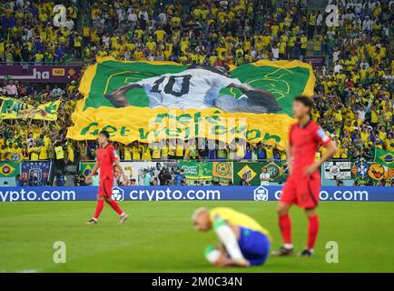 Brasilianische Fans auf den Tribünen halten ein Banner und wünschen sich, dass der ehemalige Spieler Pele während der FIFA-Weltmeisterschaft mit 16 Spielen im Stadium 974 in Doha, Katar, bald gesund wird. Foto: Montag, 5. Dezember 2022. Stockfoto