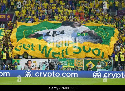 Brasilianische Fans auf den Tribünen halten ein Banner und wünschen sich, dass der ehemalige Spieler Pele während der FIFA-Weltmeisterschaft mit 16 Spielen im Stadium 974 in Doha, Katar, bald gesund wird. Foto: Montag, 5. Dezember 2022. Stockfoto