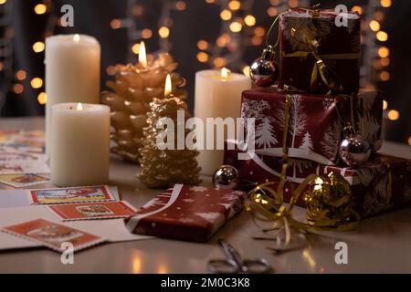 Auf dem Tisch stehen Geschenkgeschenke mit Fotoverpackung neben Kerzen Stockfoto