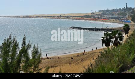 Playa El Veril Strand mit Sonnenanbetern auf Sand andere im Meer, San Agustín, Las Palmas, Gran Canaria. Maspalomas Sanddünen in der Ferne Stockfoto