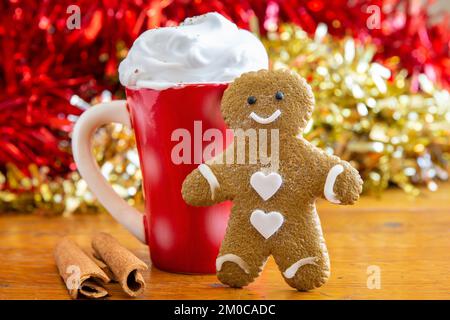 Ein köstlicher, hausgemachter Lebkuchen-Mann zu Weihnachten mit einem beruhigenden warmen Getränk, garniert mit Sahne. Festlicher Hintergrund, Platz zum Kopieren. Horizontal. Stockfoto