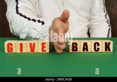 Geschäftskonzept. Ein Mann trennt die Würfel mit der Inschrift - GEBEN oder ZURÜCK Stockfoto