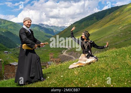 Georgische Frau tanzt und georgischer Mann spielt lokales Musikinstrument von Panduri in Ushguli, Georgia. Stockfoto