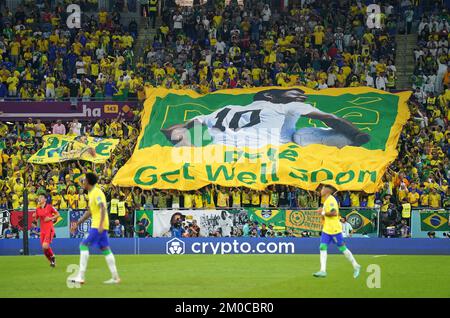 Brasilianische Fans auf den Tribünen halten ein Banner und wünschen sich, dass der ehemalige Spieler Pele während der FIFA-Weltmeisterschaft mit 16 Spielen im Stadium 974 in Doha, Katar, bald gesund wird. Foto: Montag, 5. Dezember 2022. Stockfoto