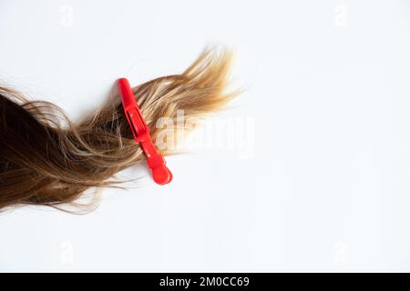 Festgeklebte weibliche Haare liegen auf weißem Hintergrund, ein Clip am Haar, ein Friseur Stockfoto