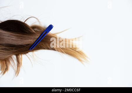 Festgeklebte weibliche Haare liegen auf weißem Hintergrund, ein Clip am Haar, ein Friseur Stockfoto