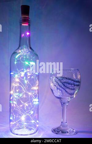 weihnachtsgirlande in einer Flasche mit einem Glas auf grauem Hintergrund Stockfoto