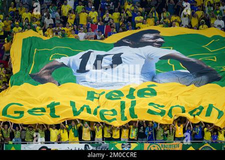 Brasilianische Fans auf den Tribünen halten ein Banner und wünschen sich, dass der ehemalige Spieler Pele während der FIFA-Weltmeisterschaft mit 16 Spielen im Stadium 974 in Doha, Katar, bald gesund wird. Foto: Montag, 5. Dezember 2022. Stockfoto