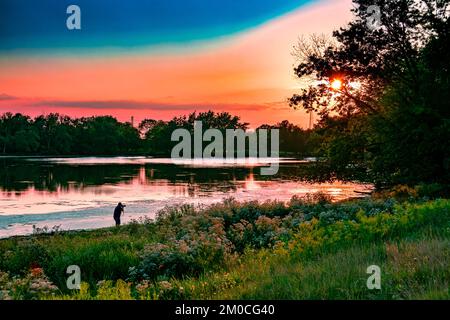 Winnetka, IL, USA - 30. August 2021: Fotograf macht ein Foto vom Sonnenuntergang in einer Lagune. In Winnetka, Illinois. Stockfoto
