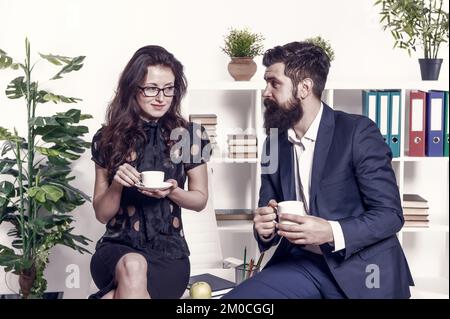 Gerüchte aus dem Büro. Bürokaffee. Ein paar Kollegen entspannen sich in der Kaffeepause. Kaffee mit Kollegen teilen. Kollegen flirten. Bärtiger Mann und attraktiv Stockfoto