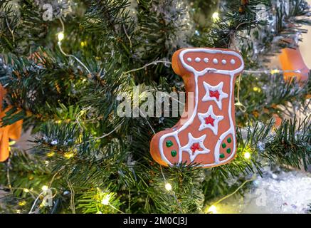 Weihnachtskuchen in Form eines Stiefels für Geschenke auf dem Weihnachtsbaum mit Girlande. Stockfoto