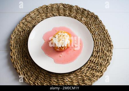 Traditionelles türkisches Quittendessert, Quitten wird in Wasser mit Zucker gekocht und mit Sahne und Haselnuss serviert. Stockfoto