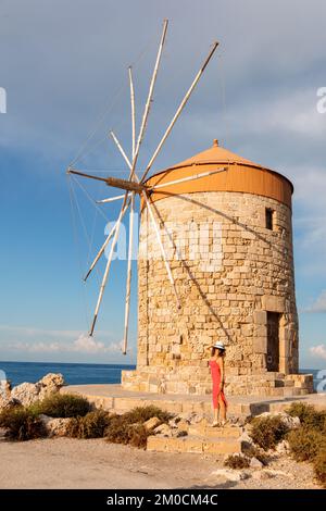 Rhodos, Griechenland - 24. August 2022: Farbenfrohe Panoramasicht auf Windmühlen mit Yachten im Hafen von Mandraki bei Sonnenuntergang, Rhodos Griechenland Stockfoto