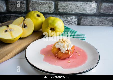 Traditionelles türkisches Quittendessert, Quitten wird in Wasser mit Zucker gekocht und mit Sahne und Haselnuss serviert. Stockfoto