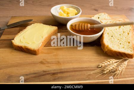 Brot mit Honig und Butter auf Holzhintergrund. Stockfoto