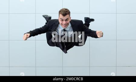 Erfolge feiern. Low-Angle-Blick auf einen aufgeregten jungen Geschäftsmann, der die Arme hält Stockfoto