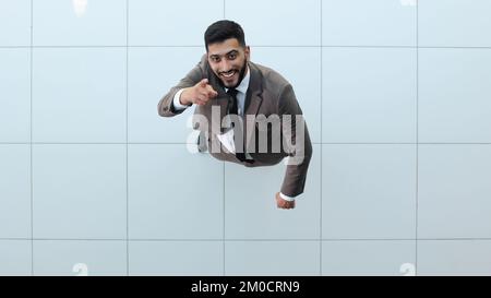 Ein gut aussehender lächelnder Geschäftsmann im Anzug, der mit gekreuzten Armen steht. Stockfoto