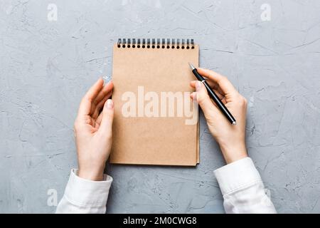 Frauenhand mit Bleistift auf Notizbuch. Frau, die am Bürotisch arbeitet. Weibliche Hand mit Bleistift und Skizzenbuch. Modellkonzept. Stockfoto