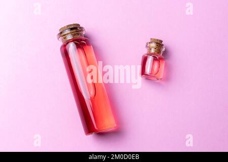 Rosa essenzielle Rose oder Grapefruit Zitrusöl auf pinkfarbenem Hintergrund Draufsicht Stockfoto