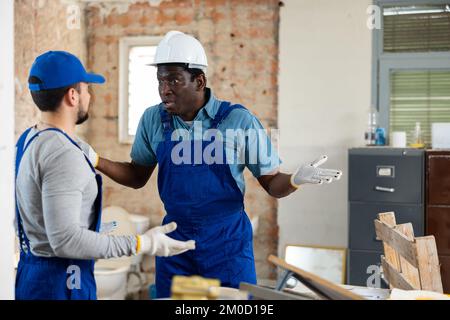 Vorarbeiter unzufrieden mit der Qualität der Reparaturarbeiten des männlichen Bauherrn Stockfoto