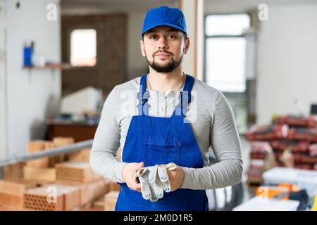Porträt eines Bauherrn in blauen Overalls im renovierten Zimmer Stockfoto