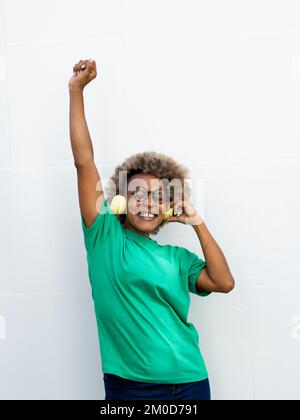 Flippige afroamerikanische Frau, die gerne mit Kopfhörern Musik hört Stockfoto