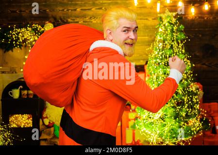 Frohe Weihnachten und Frohes neues Jahr. Der Weihnachtsmann trägt einen großen Sack voller Geschenke. Stockfoto