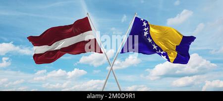 Zwei gekreuzte Flaggen Bosnien und Herzegowina und Lettland winken im Wind am bewölkten Himmel. Beziehungskonzept, Dialog, Reisen zwischen zwei Ländern. 3 Stockfoto