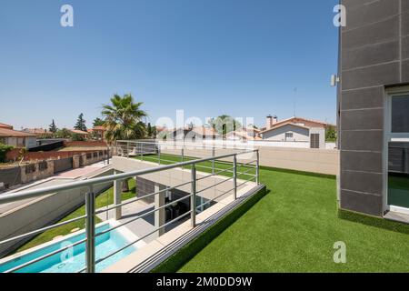 Überdachte Terrasse mit Kunstrasen und Blick auf den Sommerpool Stockfoto