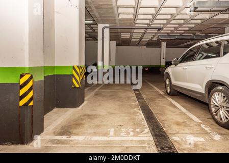 Eine Garage mit nummerierten, leeren Parkplätzen und Anti-Reib-Hinweisen auf den Säulen Stockfoto