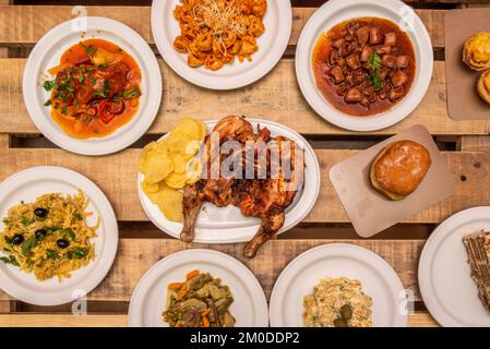 Typische spanische Tapas-Gerichte mit Salat, goldenem Kabeljau, Calamari en su tionta, gegrilltem Hähnchen, unlackierte Holzplanken Stockfoto