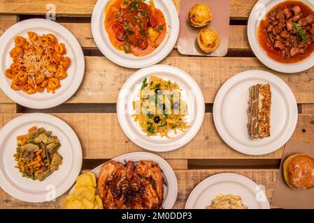 Typische spanische Tapas-Gerichte mit Salat, Gemüseeintopf, Kabeljau, goldenem Kabeljau, Calamari in der Tinte, gegrilltes Hühnchen, unlackierte Holzplanken Stockfoto