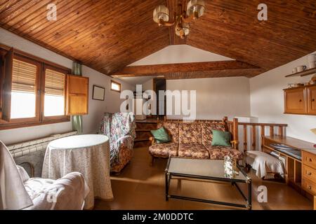 Wohnzimmer eines Penthouse mit abfallender Decke, Holzkassettendecke und alten Möbeln Stockfoto