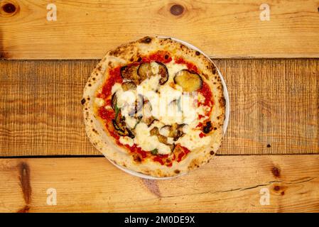 Großartige italienische Pizza mit dünner Kruste und Aubergine, etwas Basilikum mit Mozzarella-Käse und Tomaten, die in einem Steinofen gebacken wurden Stockfoto