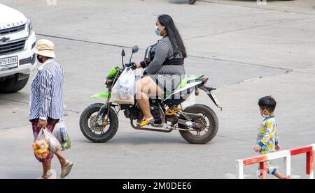 SAMUT PRAKAN, THAILAND, MÄRZ 02 2022, Eine Frau mit Gesichtsmaske fährt ein Motorrad Stockfoto