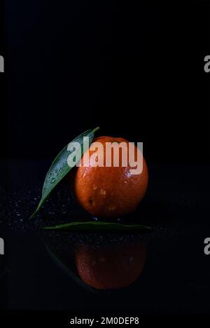 Helle Mandarine auf schwarzem Hintergrund Stockfoto