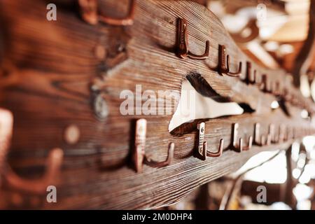 Ein rustikales Holzbrett mit Metallhaken. Kleiderbügel Gold Stahlhaken auf braunem Holzhintergrund. Stockfoto