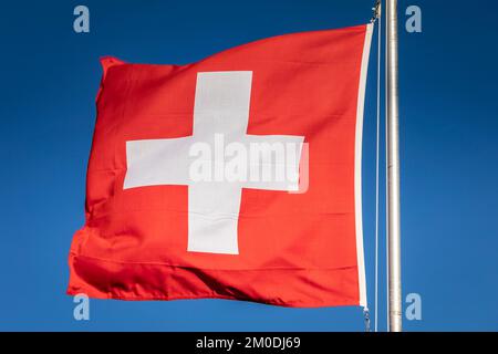 Schweizer Flagge mit blauem Himmel im Hintergrund, Schweizer Alpen Stockfoto