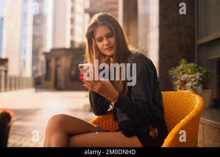 Urban Casual Woman Generation Z überprüft ihr Telefon im Sitzen in einem Café, Hände bei der Arbeit mit digitaler Technologie Stockfoto