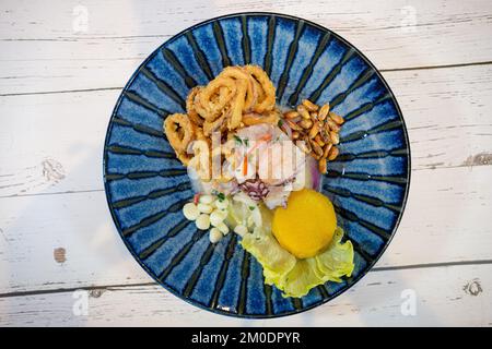 Peruanische Ceviche auf blauem Teller auf weißem Holzhintergrund Stockfoto