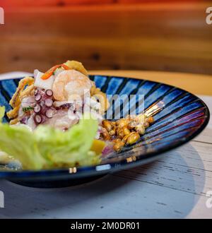 Peruanische Ceviche, serviert auf einem blauen Teller, begleitet von getoastetem Mais Stockfoto