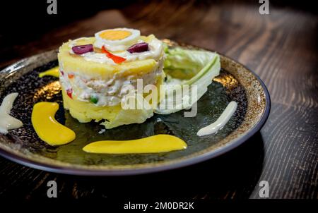 Hähnchen mit Chili, Salat und Oliven auf einem Holztisch Stockfoto