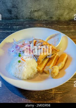 Gebratenes Fischfilet mit weißem Reis, Kartoffeln und Salat Stockfoto