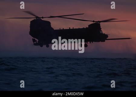 EIN US-AMERIKANISCHER Army MH-47 Chinook Helikopter mit 160. Special Operations Aviation Regiment schweben über dem Wasser als Teil des Helocast Trainings mit Marines der Bravo Company, 1. Reconnaissance Battalion, 1. Marine Division, während Steel Knight 23 vor der Küste des Marine Corps Base Camp Pendleton, Kalifornien, 2. Dezember 2022. Helocasting ist eine Methode zur Einfügung von kleinen Einheiten bei amphibischen Operationen. Steel Knight ist eine jährlich stattfindende kombinierte Feuerübung, die sicherstellt, dass 1. MARDIV für die Expeditionskampfführung der Marine in umkämpften Räumen optimiert und speziell für die Zukunft gebaut wurde Stockfoto