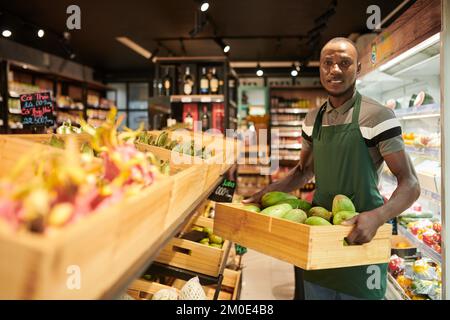 Supermarktkraft bringt Mangokiste zur Produktionsabteilung im Supermarkt Stockfoto