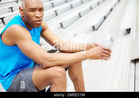 Es ist fast Zeit für die nächste Runde. Nahaufnahme eines männlichen Läufers, der auf dem Dachsparren sitzt und von der Kamera wegschaut. Stockfoto